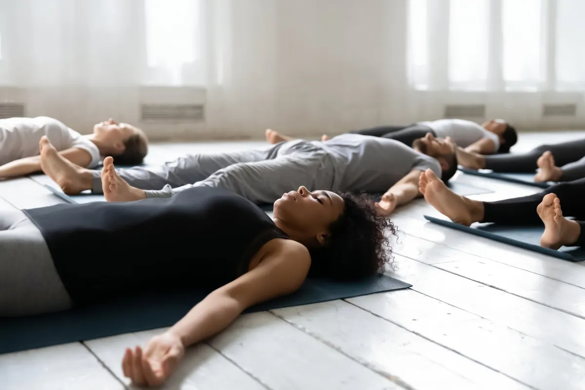 Séance de relaxation en entreprise : des participants allongés sur des tapis de yoga, les yeux fermés
