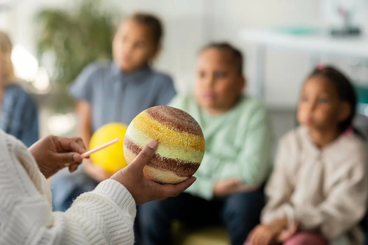 Une médiatrice présente une maquette de planète à un groupe d’enfants attentifs